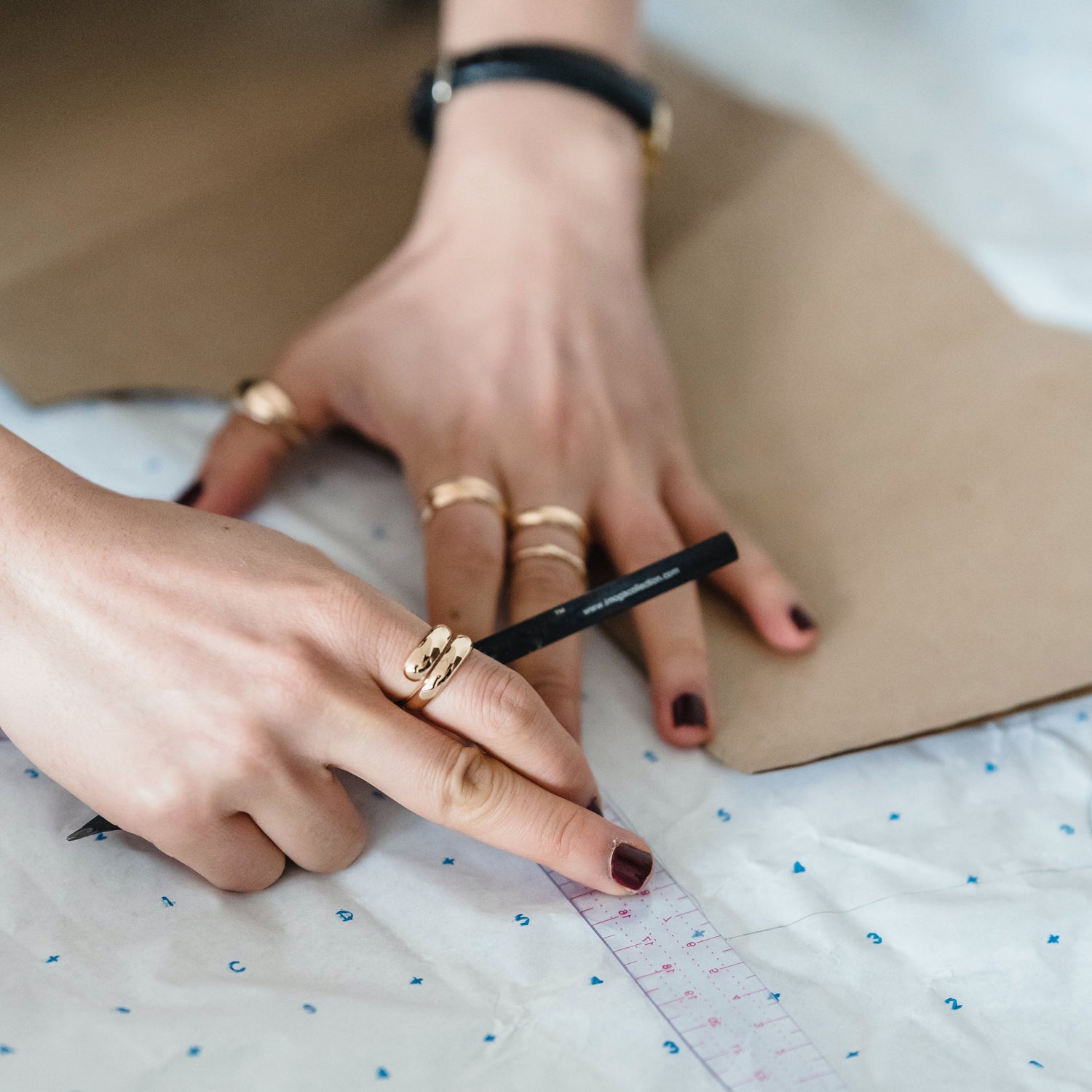 Pair of hands measuring and marking out fabric pattern to then cut to size